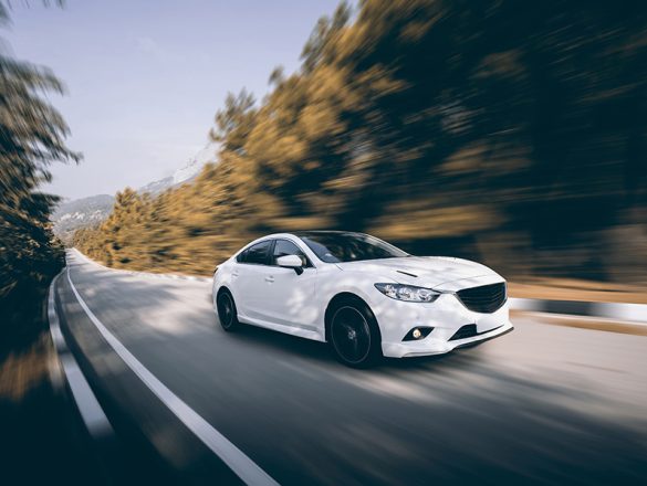 White car speed driving on asphalt road at daytime White car speed driving on asphalt road at daytime